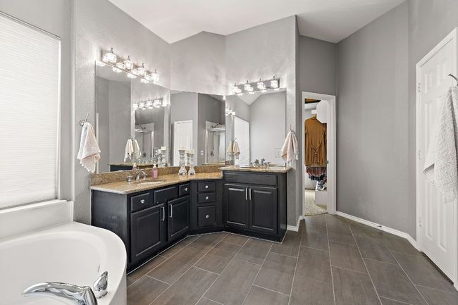 Bathroom featuring double vanity, a shower stall, a garden tub, baseboards, and new flooring. | Image 19