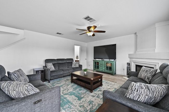 Living area with ceiling fan, light wood-style flooring, a fireplace, and baseboards | Image 10
