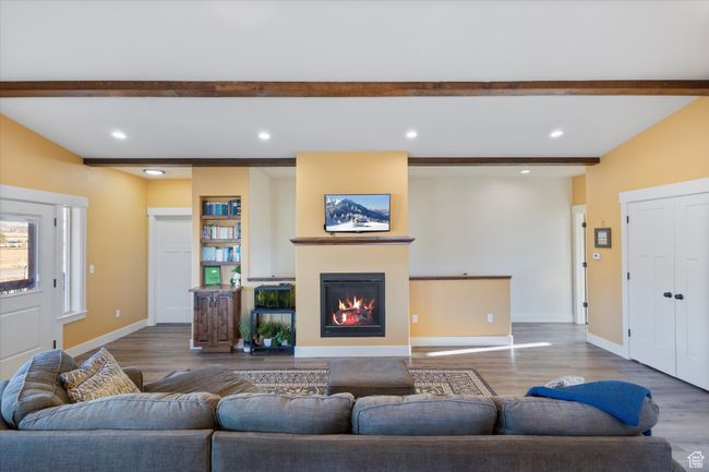 Living area with beamed ceiling, baseboards, a glass covered fireplace, and wood finished floors | Image 17
