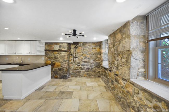 Kitchen with open shelves, a chandelier, white cabinetry, a peninsula, and dark stone counters | Image 6