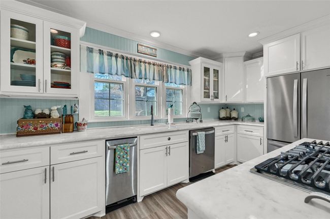 Kitchen with stainless steel appliances, white cabinetry, light wood finished floors, glass insert cabinets, and recessed lighting | Image 15