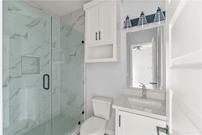 Full bath featuring toilet, vanity, and a marble finish shower | Image 12