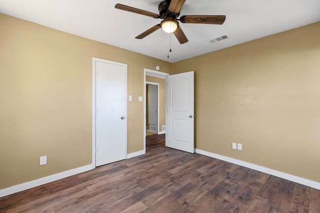 Unfurnished bedroom featuring dark wood-style floors, visible vents, ceiling fan, and baseboards | Image 21