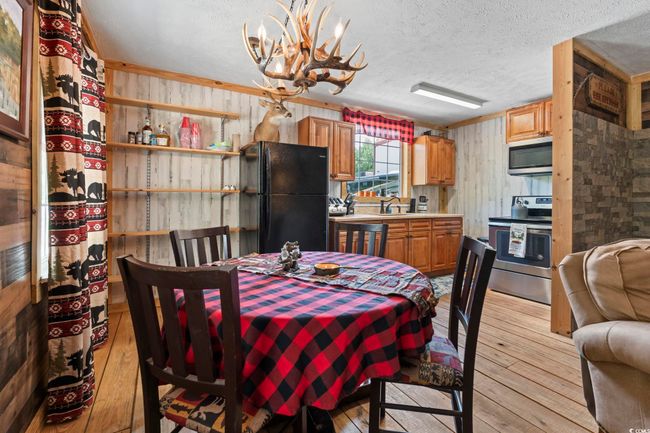 Dining space with light wood-type flooring, wooden walls, a chandelier, and a textured ceiling | Image 15