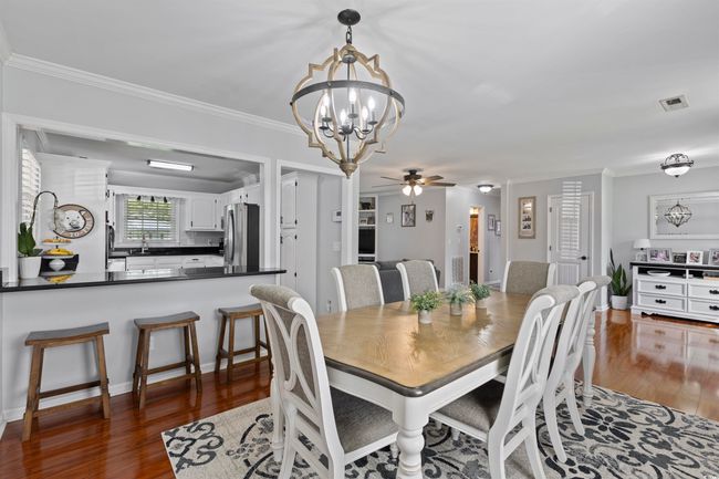 Dining space with a chandelier, wood finished floors, ceiling fan, and ornamental molding | Image 5