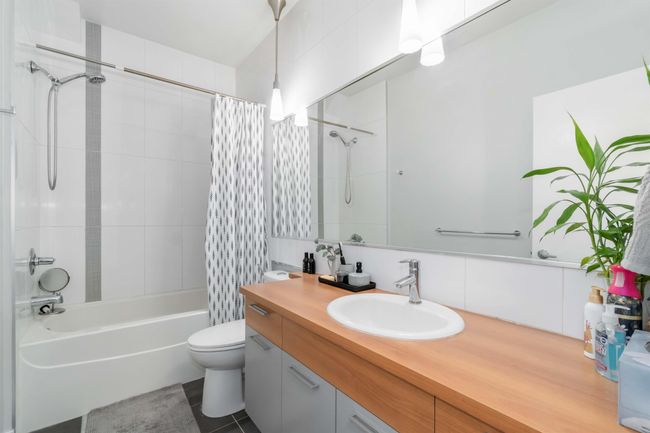 Bathroom featuring tasteful backsplash, toilet, shower / bath combination with curtain, vanity, and tile walls | Image 22