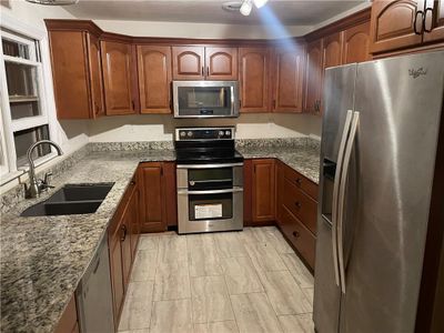 Kitchen with appliances with stainless steel finishes, sink, and light stone counters | Image 2