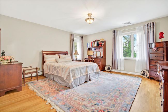 Bedroom featuring multiple windows, baseboard heating, light wood finished floors, and baseboards | Image 36