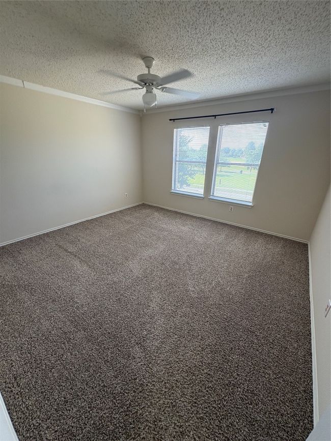 Carpeted spare room featuring ceiling fan, crown molding, and a textured ceiling | Image 18