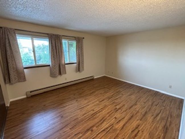 Empty room featuring a baseboard radiator, a textured ceiling, wood finished floors, and baseboards | Image 8