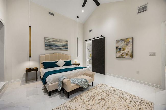 Experience elevated comfort in this stunning primary suite featuring soaring vaulted ceilings, sleek modern pendant lighting, and expansive sliding glass doors that open to a serene outdoor escape. Polished marble-look floors and a neutral palette create a refined, tranquil atmosphere—your private retreat awaits. | Image 22