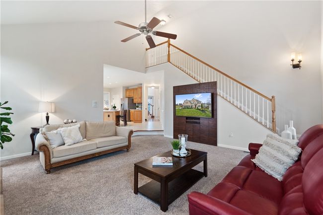 Soaring ceilings, custom wood-wall tv stand and back staircase are featured in the great room. | Image 12