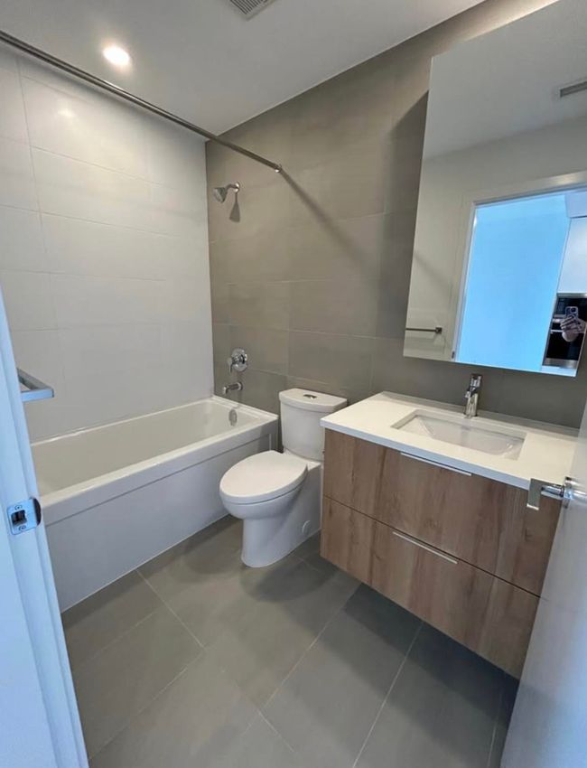 Full bathroom featuring tile walls, vanity, toilet, tub / shower combination, and tile patterned flooring | Image 12