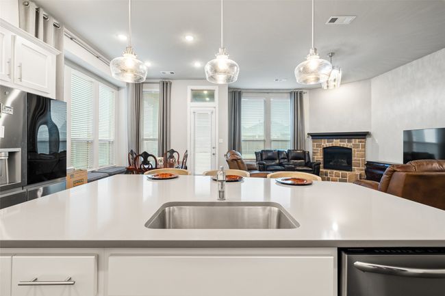 Kitchen featuring sink, hanging light fixtures, dishwasher, a kitchen island with sink, and white cabinets | Image 5