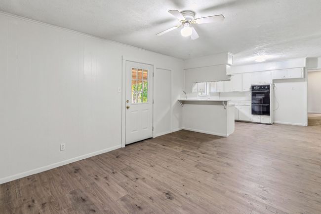 Kitchen with a peninsula, white cabinets, a kitchen breakfast bar, light wood finished floors, and ceiling fan | Image 21