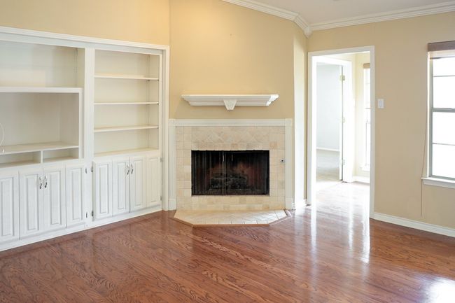 Unfurnished living room featuring a tile fireplace, wood finished floors, and ornamental molding | Image 7