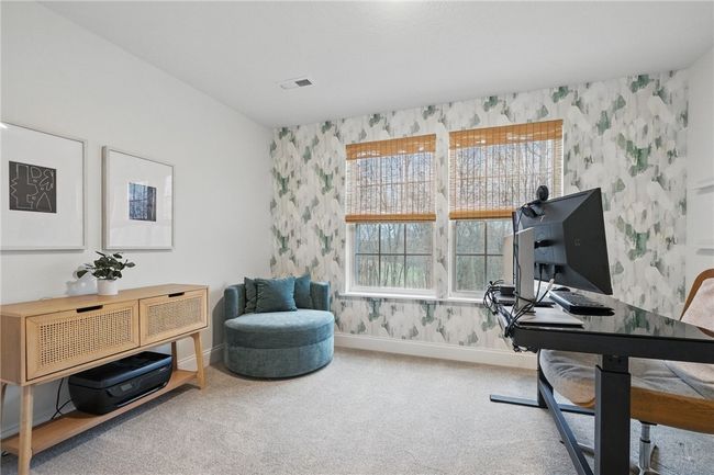 Stylish and functional bonus room tucked behind sliding barn doors with built-in shelving. Perfectly suited as a private home office, study, or creative space, featuring large windows that fill the room with natural light and offer serene wooded views. | Image 33