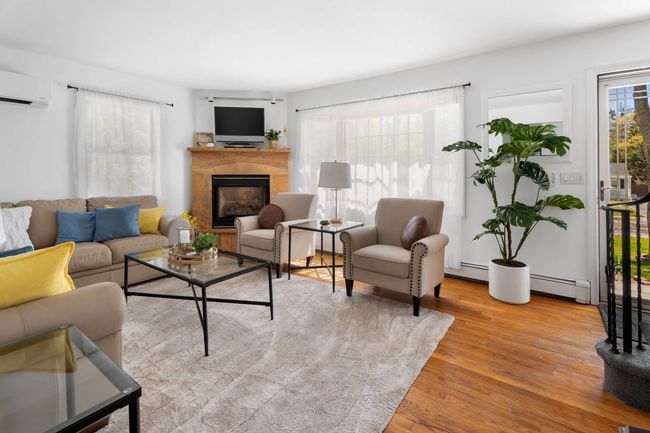 Living room featuring a tile fireplace, a baseboard heating unit, a wall unit AC, and light hardwood / wood-style flooring | Image 17