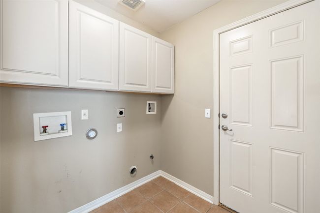 Washroom with hookup for a gas dryer, washer hookup, hookup for an electric dryer, cabinet space, and baseboards | Image 31