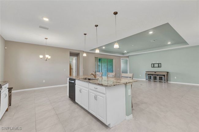 Kitchen featuring a notable chandelier, a center island with sink, a tray ceiling, dishwasher, and a sink | Image 28