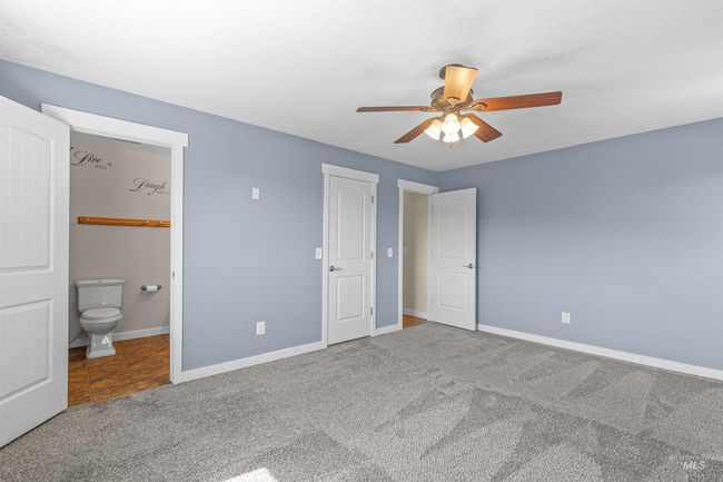Unfurnished bedroom with carpet floors, connected bathroom, ceiling fan, and tile patterned floors | Image 18