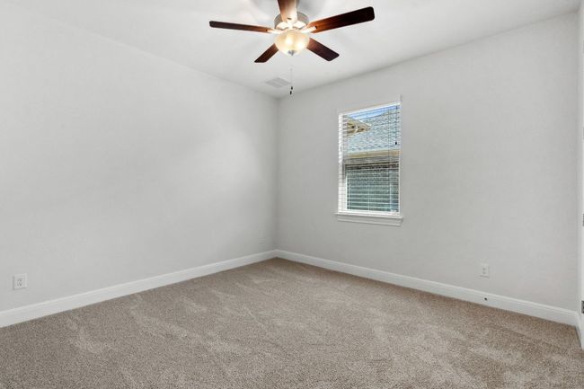 Empty room with visible vents, light colored carpet, baseboards, and ceiling fan | Image 26