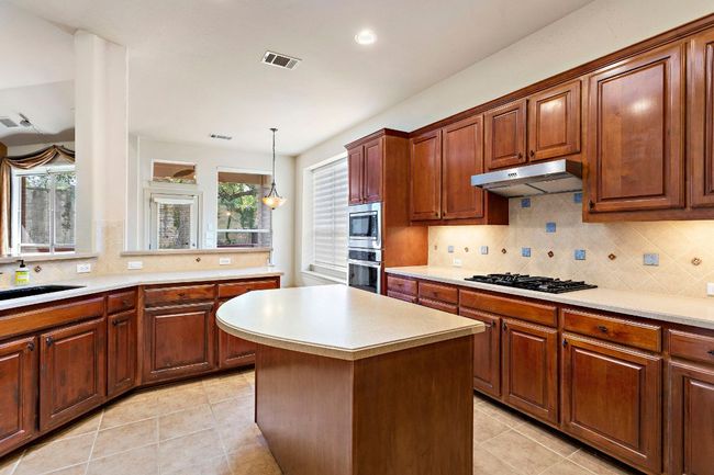 Kitchen with light tile patterned floors, light countertops, under cabinet range hood, and appliances with stainless steel finishes | Image 15