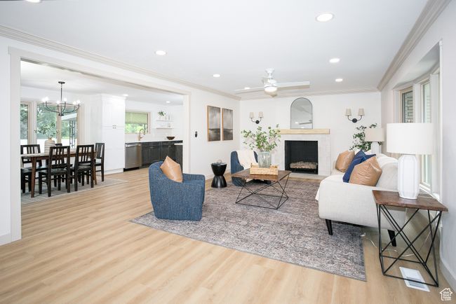 Living room with a chandelier, light wood-style flooring, recessed lighting, a fireplace with flush hearth, and ornamental molding | Image 18