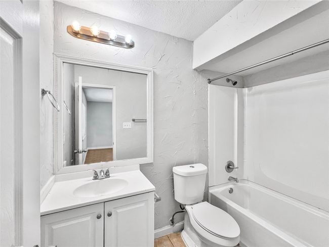Bathroom featuring a textured ceiling, shower / tub combination, vanity, and a textured wall | Image 6