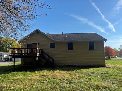 Rear view of house with a deck, central AC unit, and a lawn | Image 3