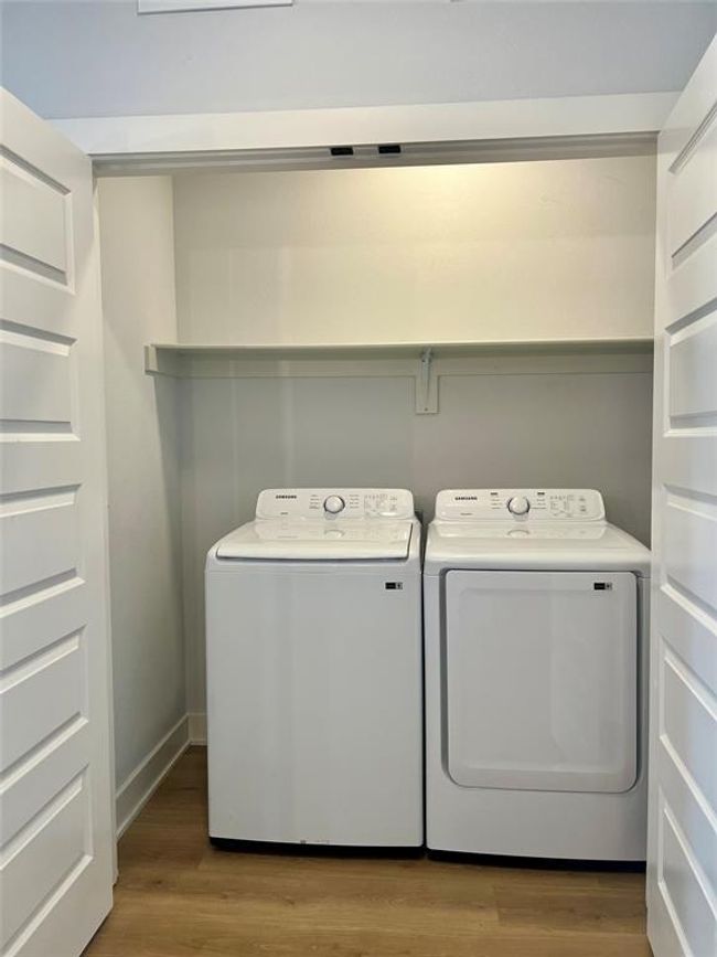 Laundry area featuring washing machine and clothes dryer and wood finished floors and shelf | Image 11