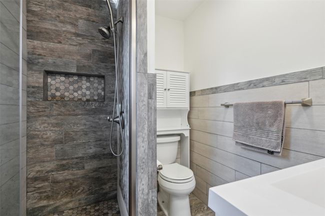 Bathroom with wainscoting, a shower stall, toilet, and tile walls | Image 21