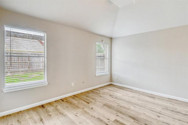 Two large windows fill the room with natural light and offer peaceful views of the backyard, creating a bright and relaxing atmosphere. | Image 19