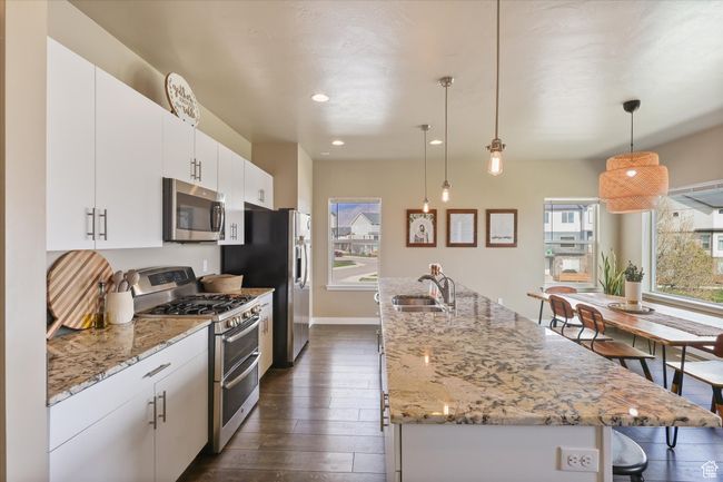 Kitchen featuring a sink, a breakfast bar, stainless steel appliances, a center island with sink, and dark wood finished floors | Image 11