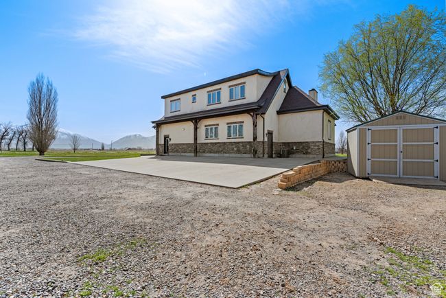 View of front of home featuring stucco siding, a chimney, a mountain view, an outbuilding, and a storage unit | Image 5