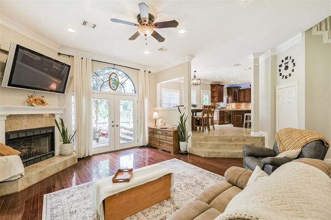 Cozy family room with a fireplace and French doors opening to a spacious deck. | Image 7