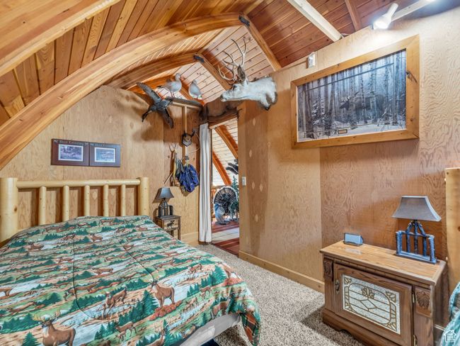 Bedroom featuring wood ceiling, carpet floors, vaulted ceiling, and wood walls | Image 18
