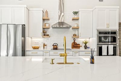 Kitchen featuring appliances with stainless steel finishes, light stone countertops, wall chimney range hood, and tasteful backsplash | Image 3