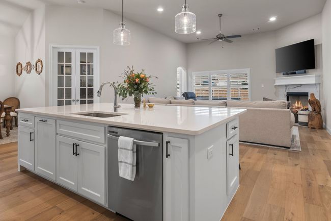 Kitchen with a kitchen island with sink, a sink, open floor plan, french doors, and light wood finished floors | Image 9
