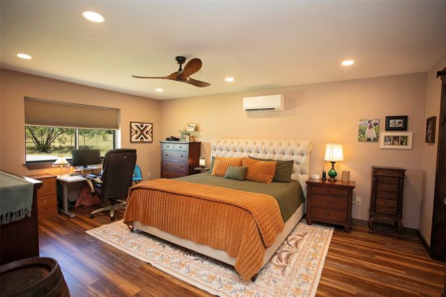Bedroom featuring a wall unit AC, wood finished floors, an office area, a ceiling fan, and recessed lighting | Image 36