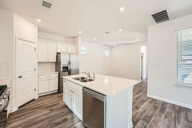 Kitchen with a sink, dark wood-style floors, visible vents, and stainless steel appliances | Image 9
