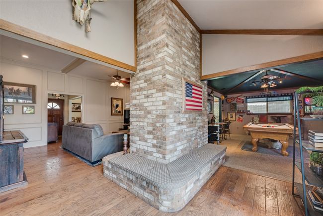 Recreation room with a ceiling fan, pool table, wood finished floors, a decorative wall, and high vaulted ceiling | Image 12