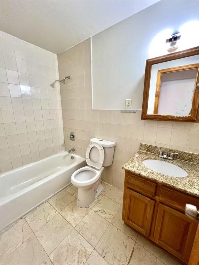 Full bathroom with toilet, tile walls, tiled shower / bath combo, and vanity | Image 6