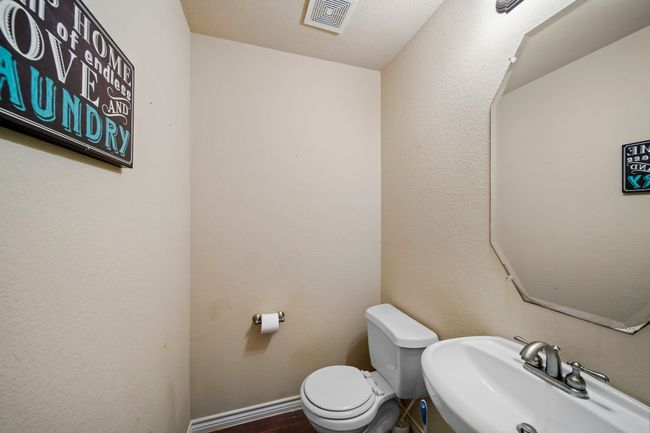 Half bathroom featuring toilet, baseboards, a sink, visible vents, and wood finished floors | Image 34