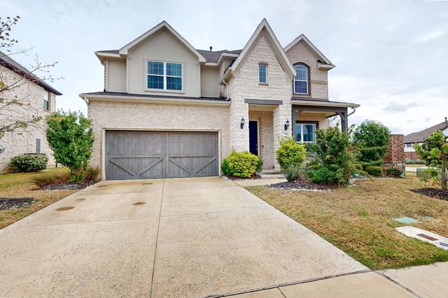 View of front of house with an attached garage, stone siding, stucco siding, brick siding, and driveway | Image 4