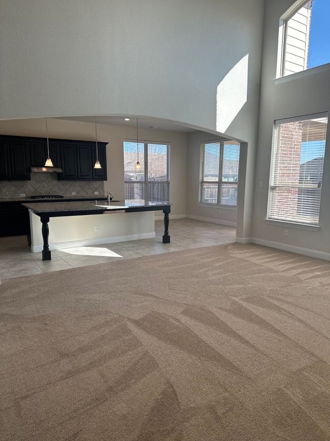 Kitchen with light carpet, extractor fan, open floor plan, and a towering ceiling | Image 11