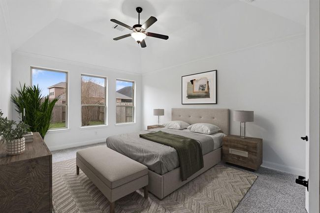 This inviting primary bedroom, conveniently located on the first floor, features soft carpet, an abundance of natural light from multiple windows, and a striking high sloped ceiling that adds elegance and character to the space. *Virtually Staged* | Image 10