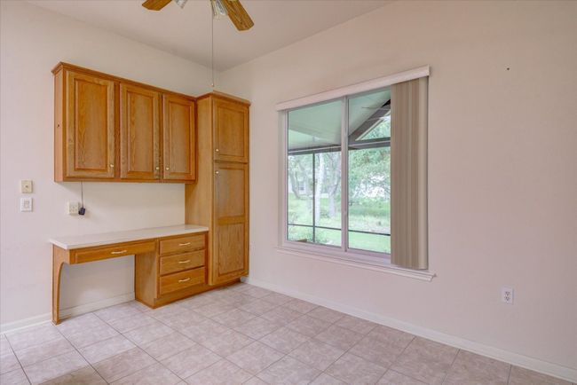 Office with built in desk, ceiling fan, and light tile patterned floors | Image 14