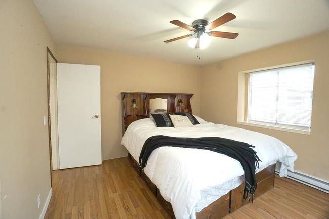 Bedroom with wood finished floors, ceiling fan, and a baseboard radiator | Image 11