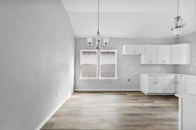 Unfurnished dining area with a chandelier, lofted ceiling, and wood finished floors | Image 4
